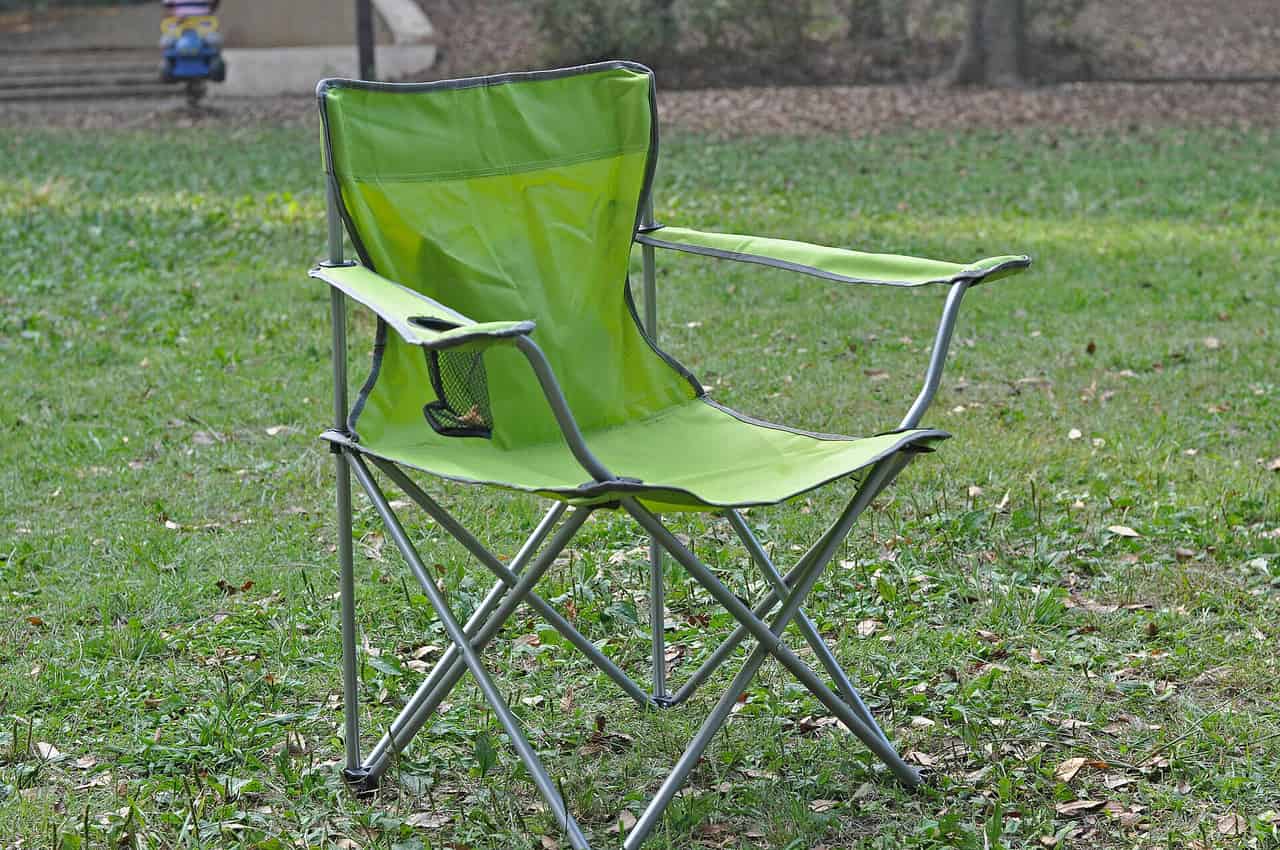 A folding camping chair set up beside a fire ring at dusk