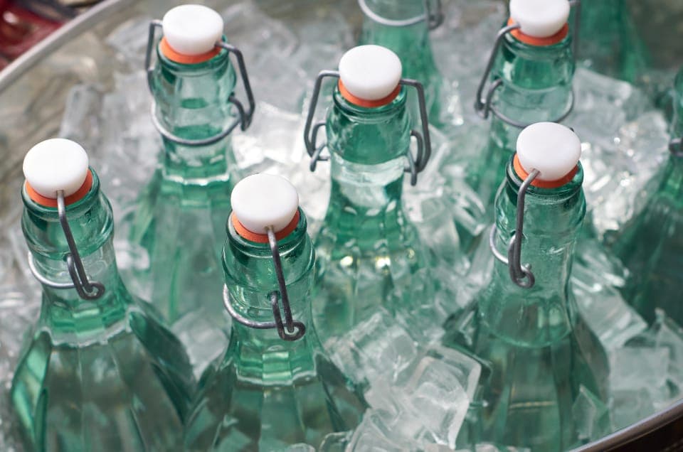 A soft-sided cooler packed with ice at a campsite