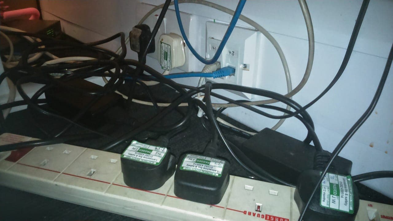 A universal travel adapter plugged into a wall socket with cables attached