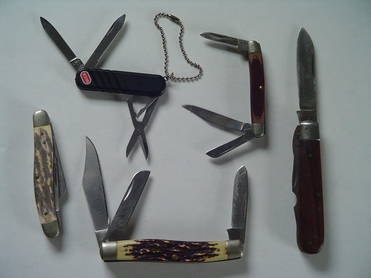 A folding pocket knife and a fixed-blade knife on a wooden surface