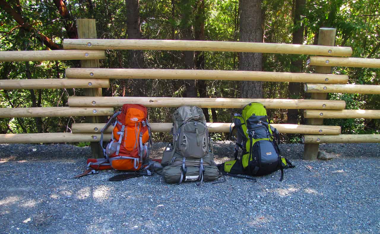 A loaded hiking backpack resting on a rock on a mountain trail